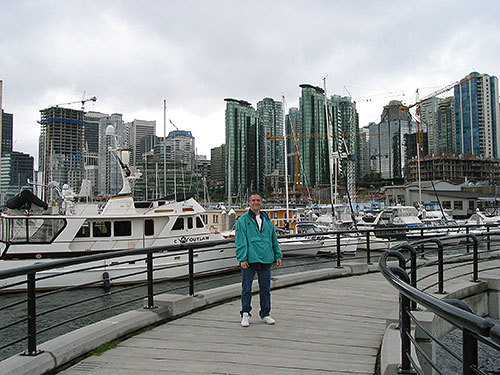 Pat at waterfront with boats and skyline behind