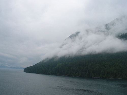 Mountain with low hanging clouds beyond the water