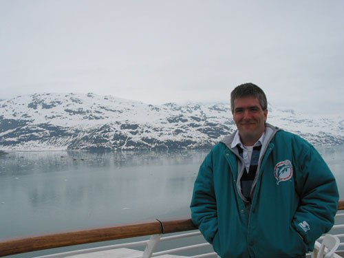 Pat standing at rail of ship with glacier in background