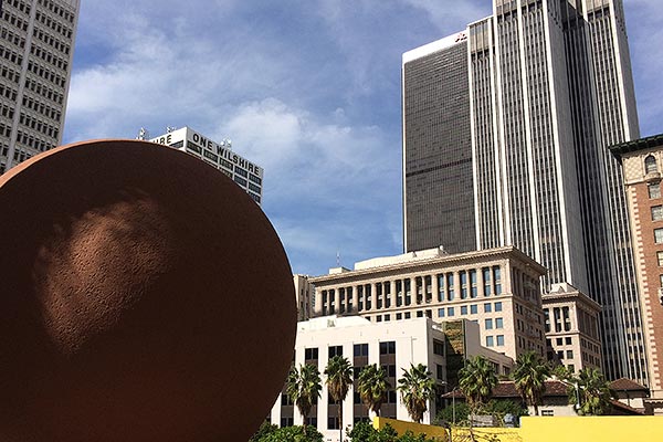 Round sculpture in front of the Los Angeles skyline
