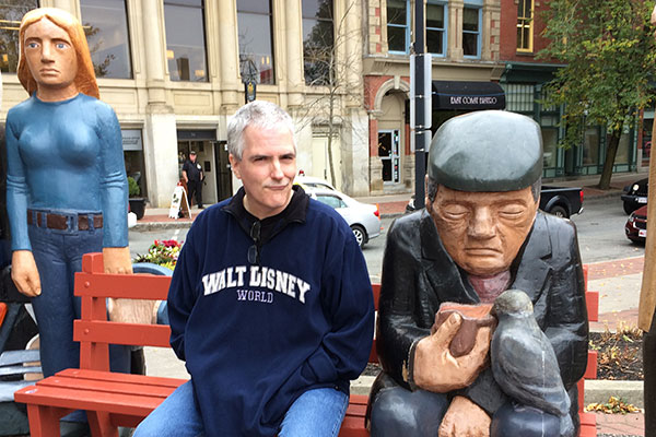 Pat sits next to statue of old man
