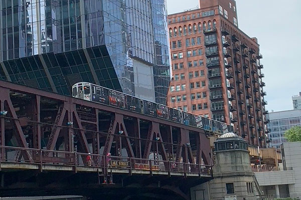 CTA train travels over a bridge with buildings in the background