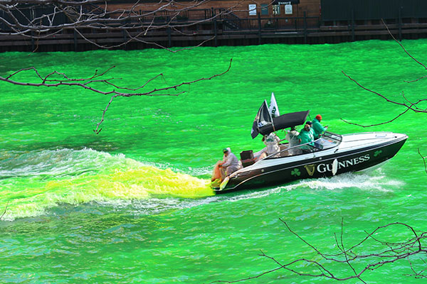 Person drops dye into the Chicago River from a boat