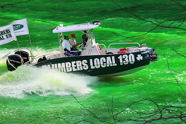Boat with sign Plumber Local 130 as the Chicago River is dyed green