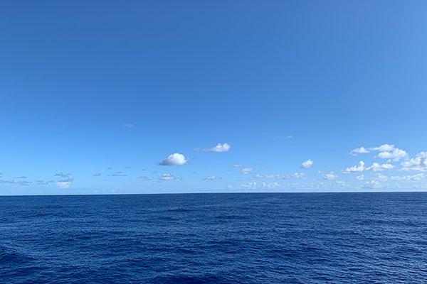 View of water from ship with a few clouds in sky