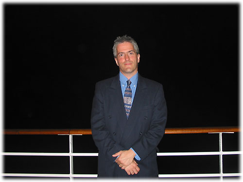 Pat in suit stands by railing at night