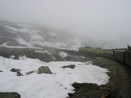 Train approaches bridge with snow on ground