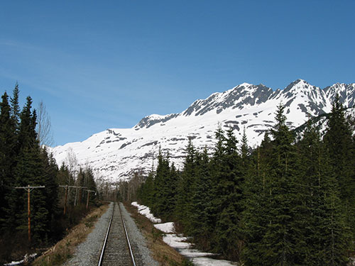 View of mountains covered with snow from back of train