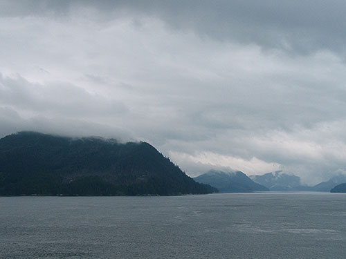 Water with mountain shrouded in clouds