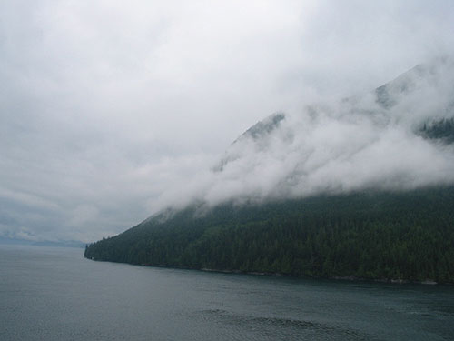 Mountain with low hanging clouds beyond the water