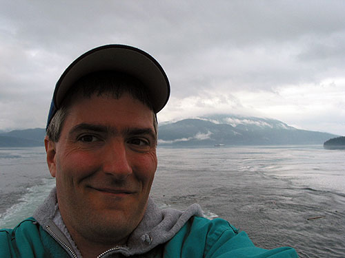 Pat with water and mountains behind him