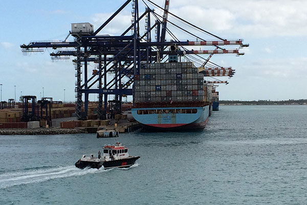 Boat moves past docked ship