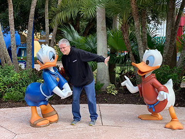 Pat standing by Donald and Daisy Duck statues