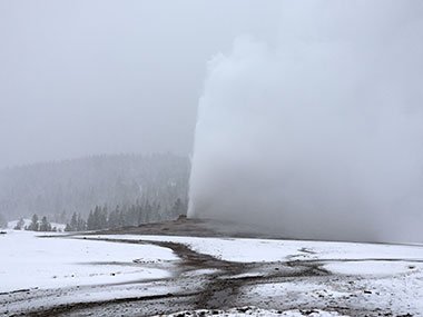 Yellowstone National Park - Old Faithful erupts while it snows