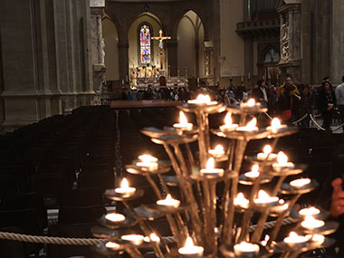 Candles burn with altar in background