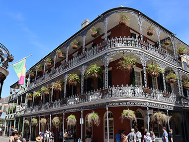 People stand in street under a balcony