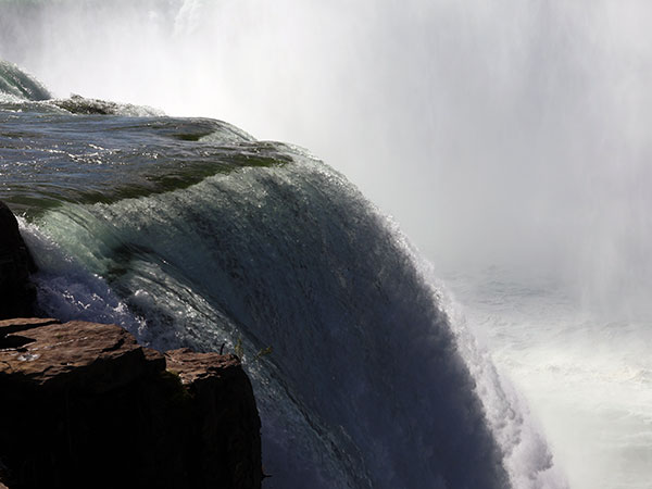 Close up of water flowing over Niagara Falls on American side with mist in background