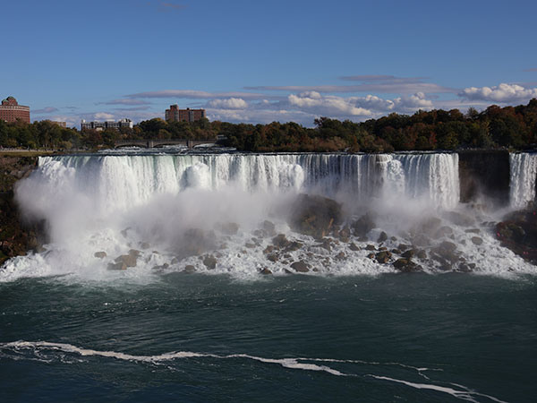 Few white fluffy clouds in the distance of Niagara Falls as viewed from Canadian side