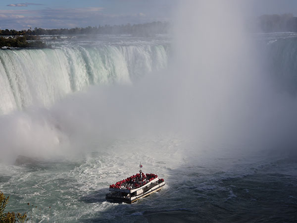 Boat approaches mist filled waterfall area