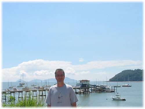 Pat stands on land with water behind him