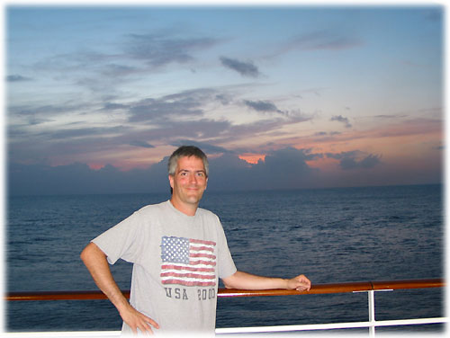 Pat with arm on rail while sun sets behind him