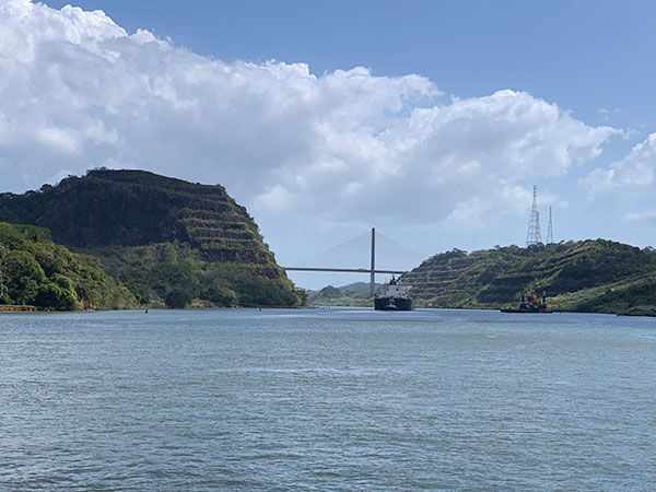 In the distance a boat passes under a bridge