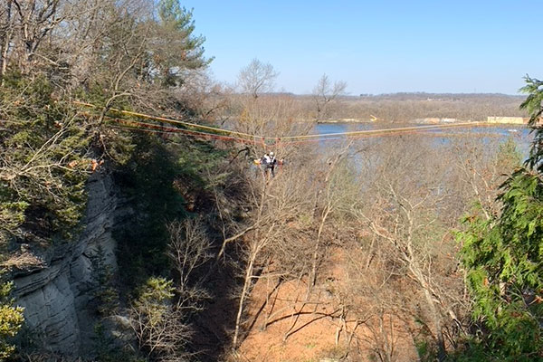 Rescue worker in the air with a basket holding a rescue mannequin