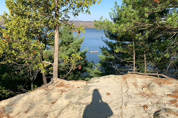 Pat's shadow with boat on river in background