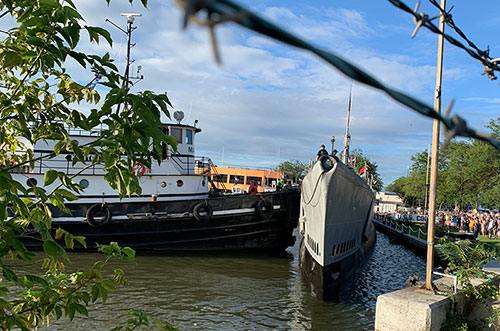Submarine is pushed into the dock by a tugboat